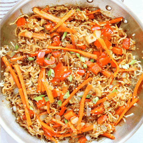 Noodles with veggies in skillet.