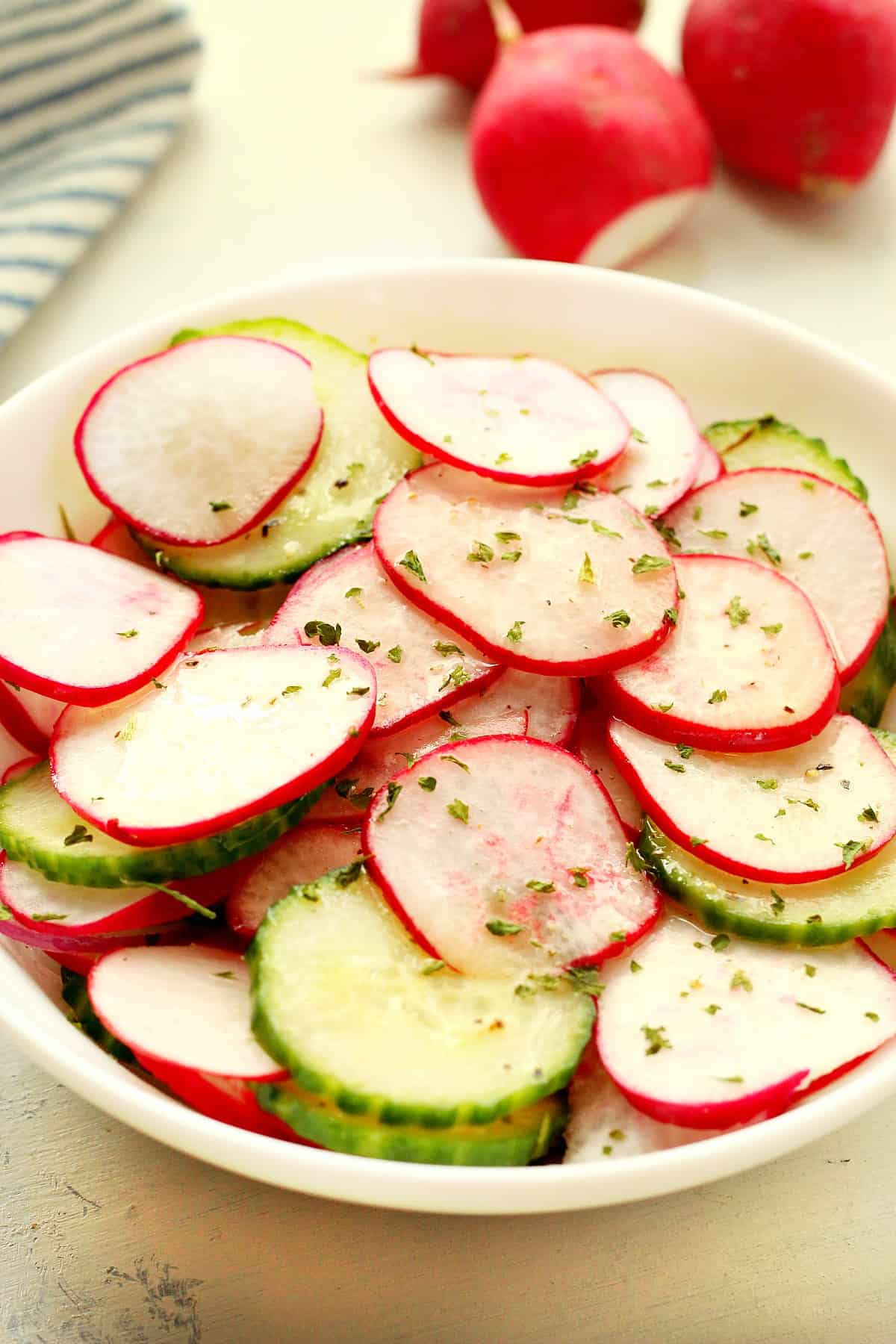 Sliced radishes and cucumber in a bowl.