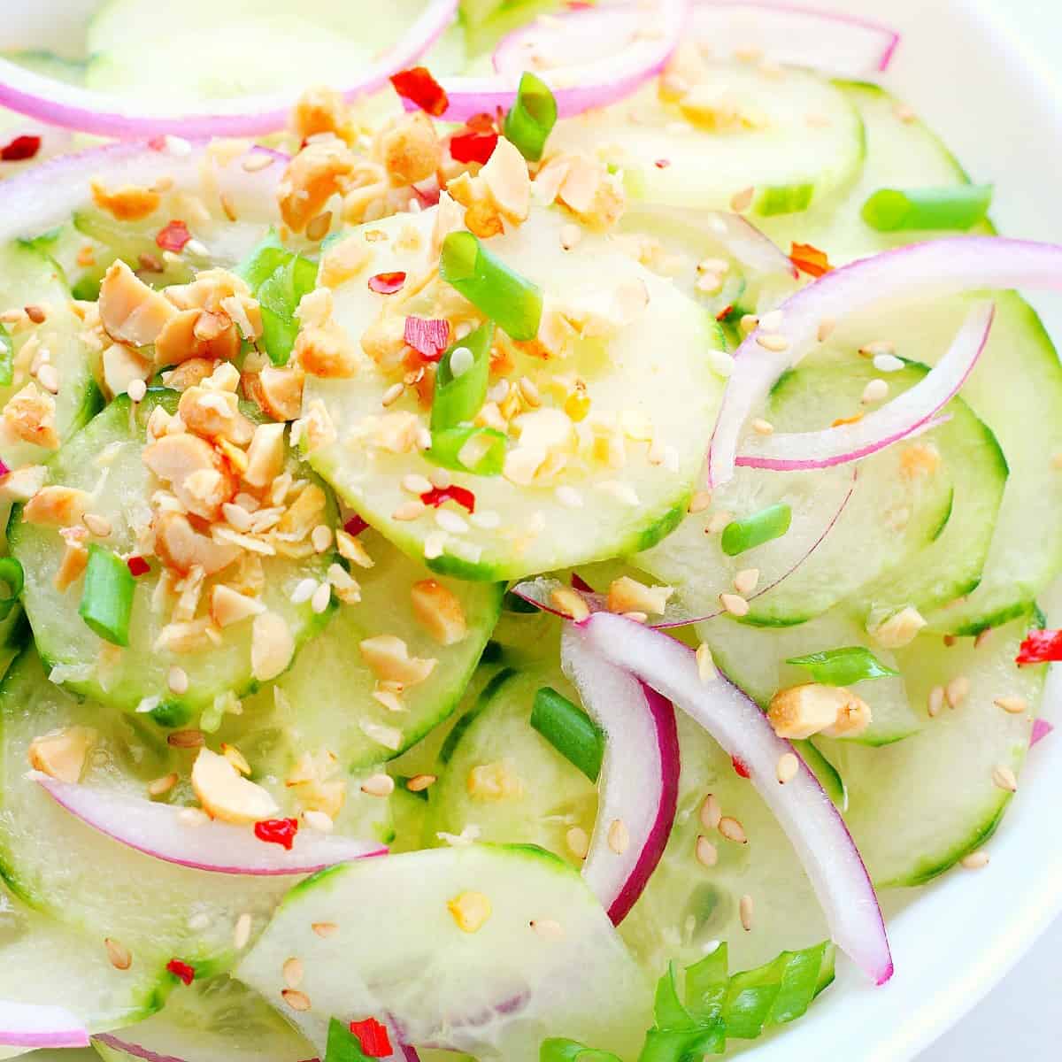 Sliced cucumbers and red onion in a bowl.