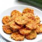 Fried zucchini on a plate next to air fryer.