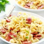 Cabbage and noodles with sausage on a white plate.