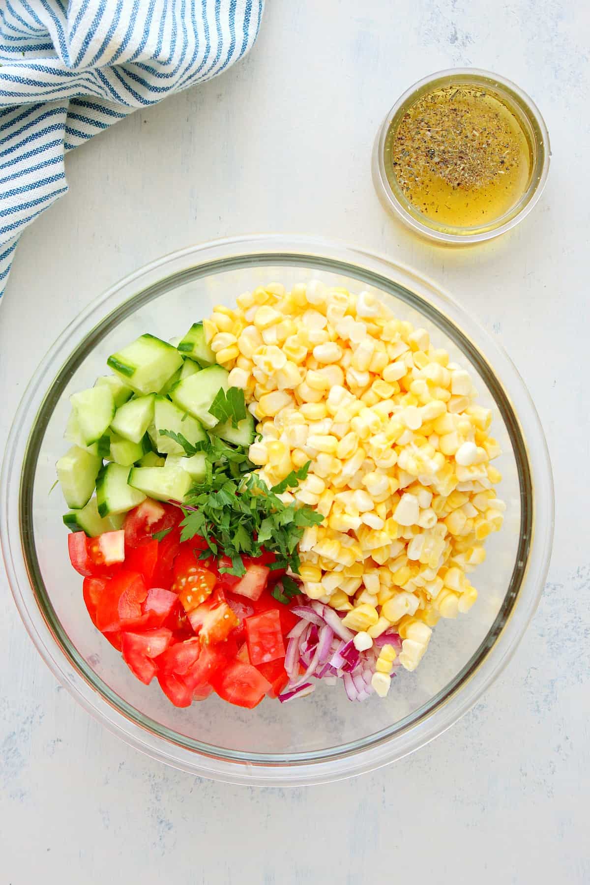 Ingredients for corn salad in a glass bowl.