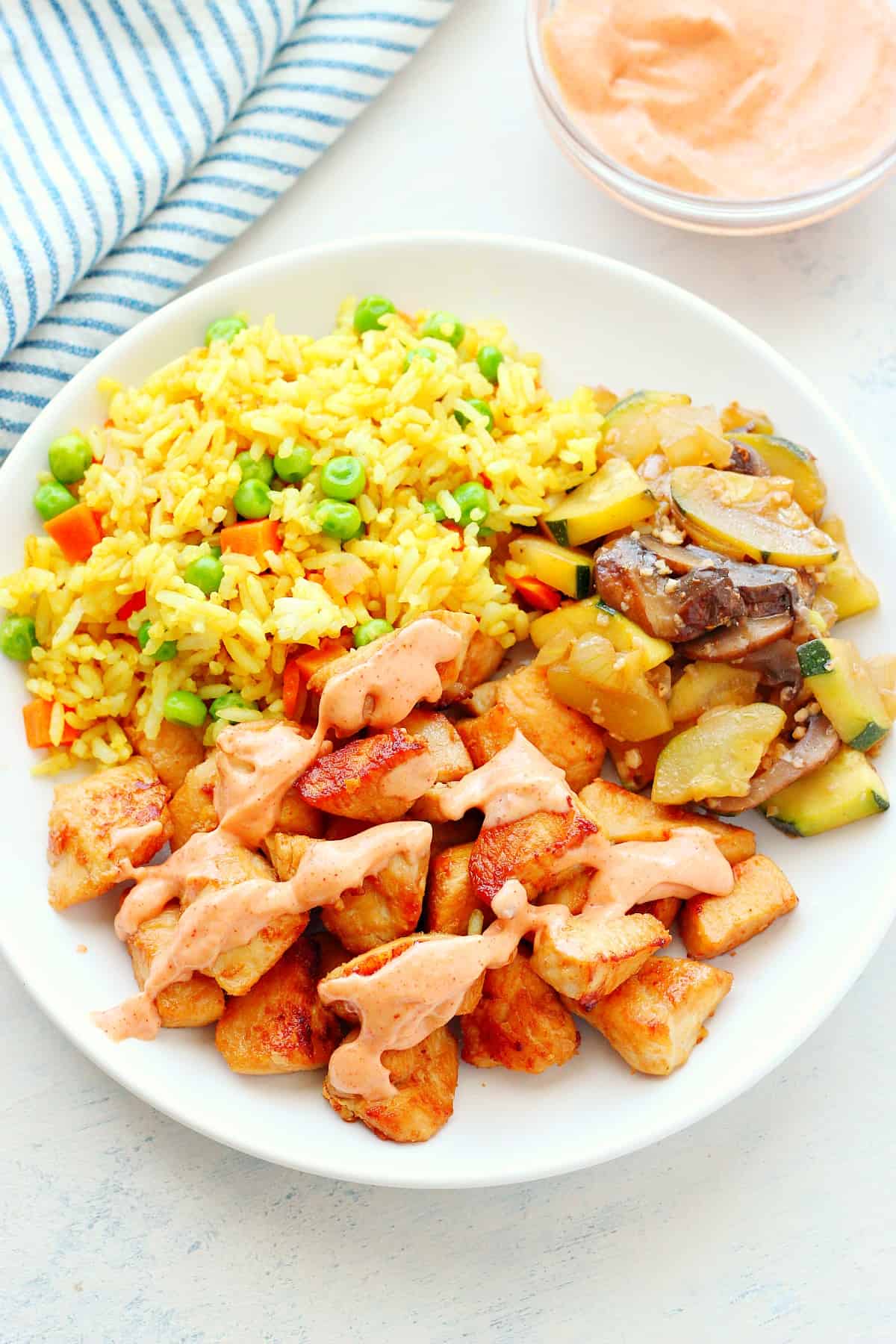 Chicken, fried rice and sauteed veggies on a plate. 