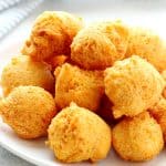 Fried hush puppies on a white plate.