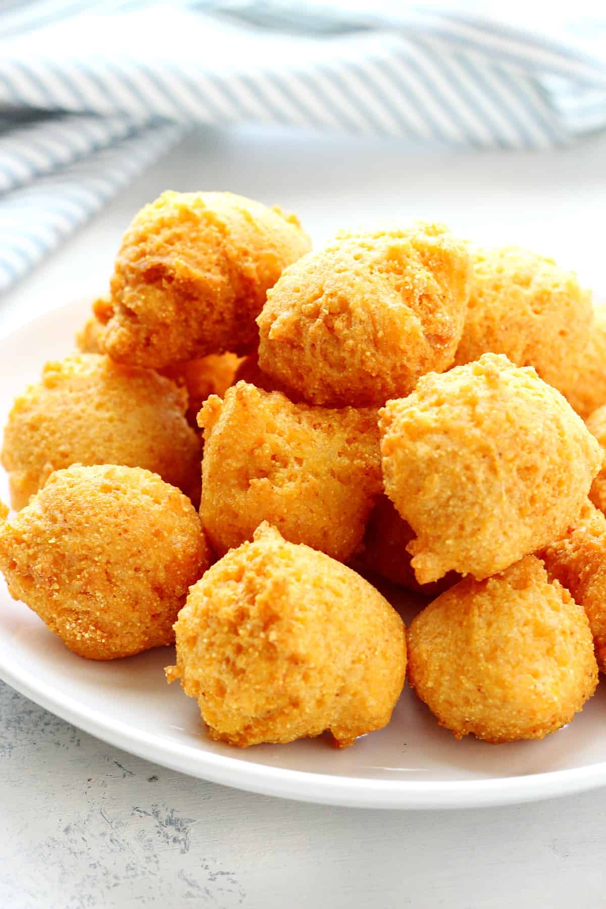 Fried hush puppies on a white plate.