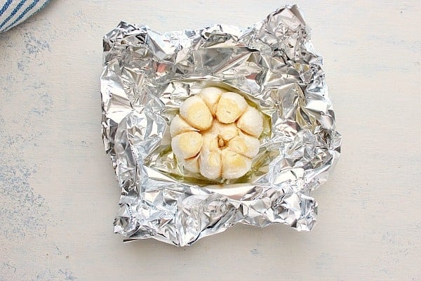 Fresh garlic bulb on a sheet of aluminum foil.