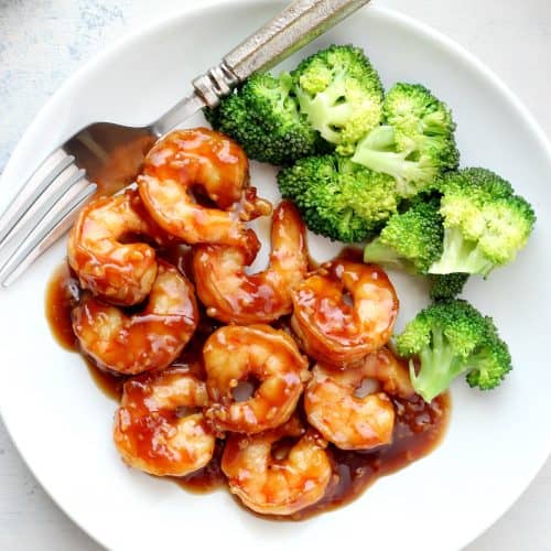 Shrimp with sauce and broccoli on a plate.