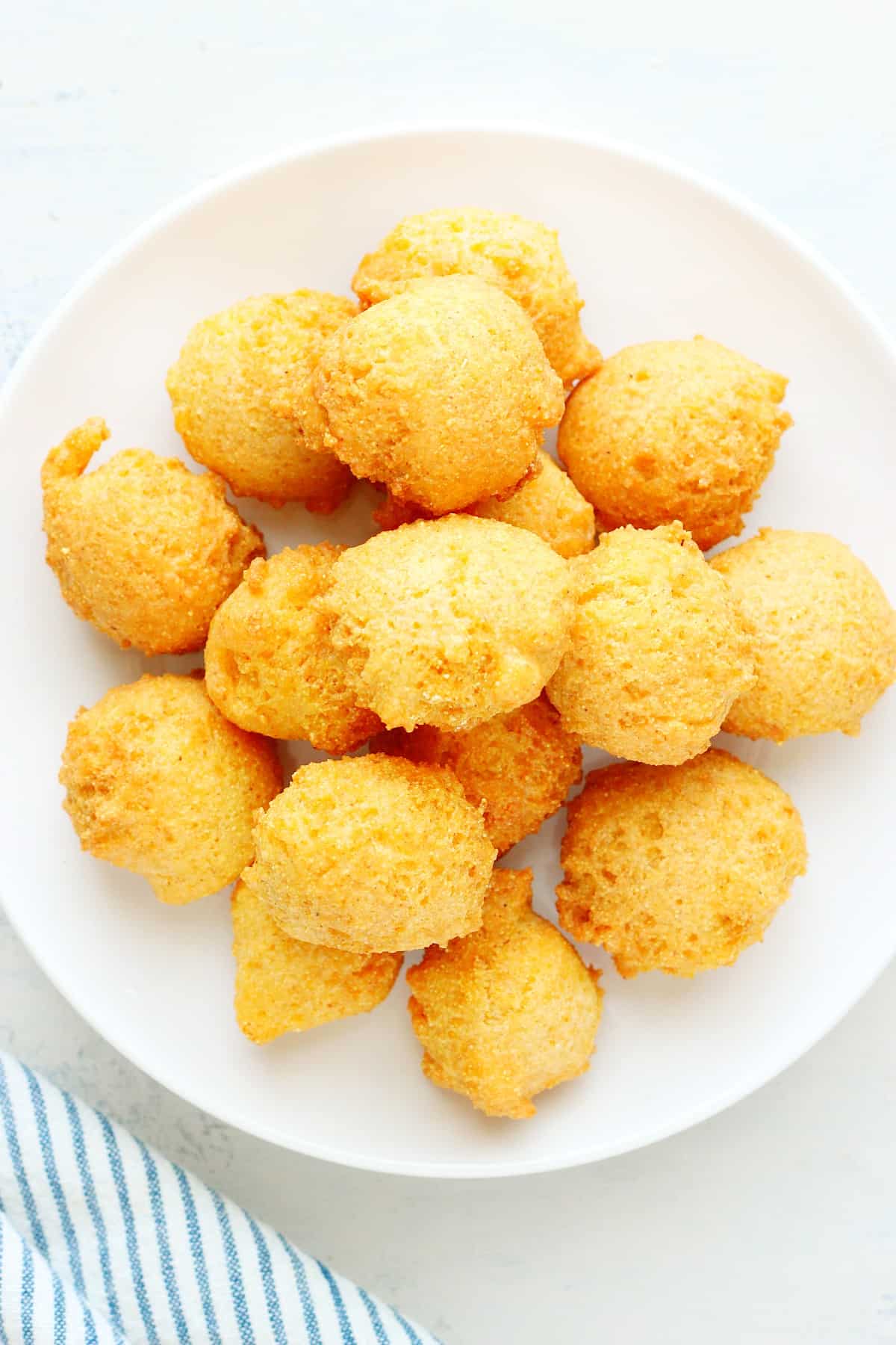 Hush puppies on a plate on a board.