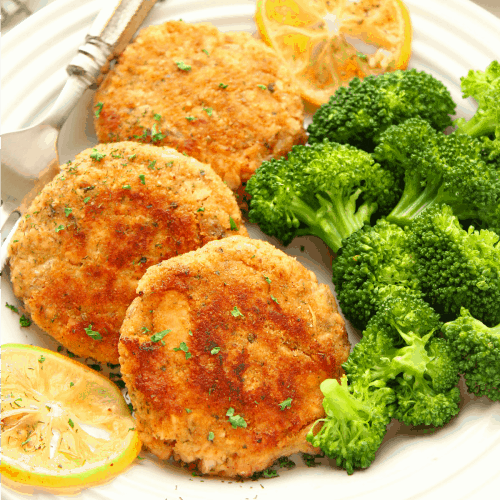 Salmon patties with broccoli on a plate.