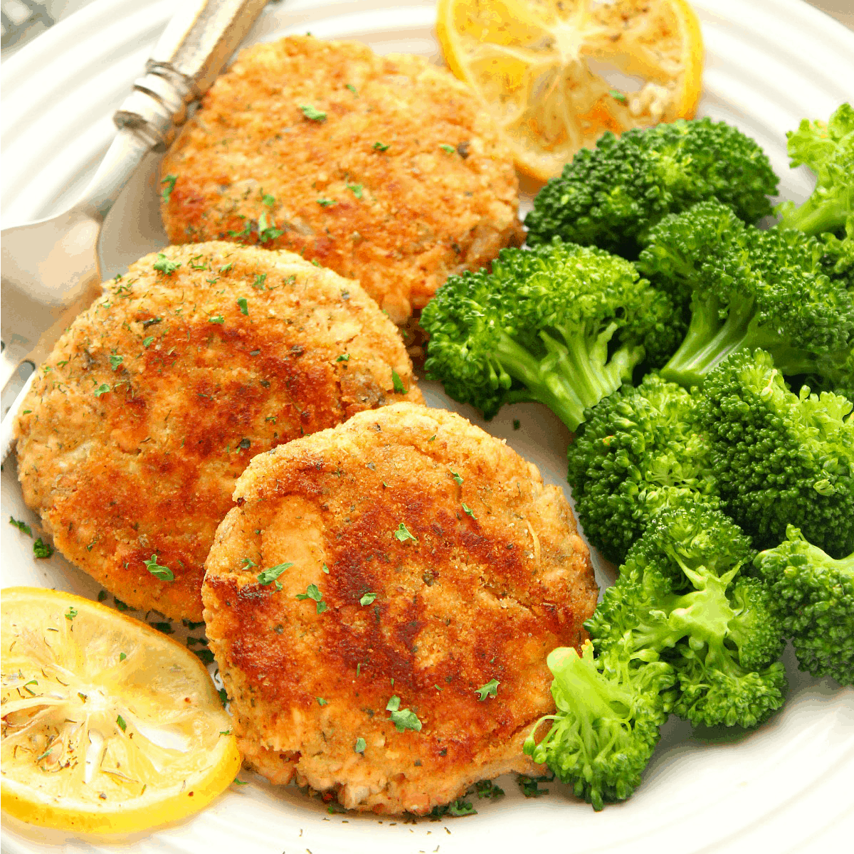 Salmon patties with broccoli on a plate.
