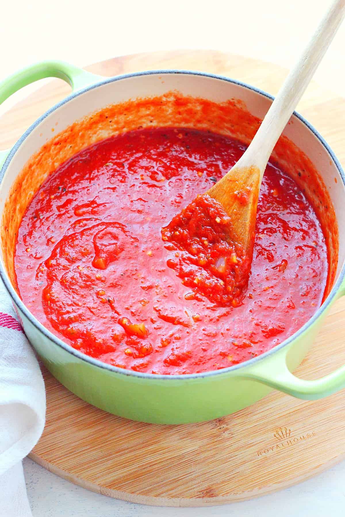 Tomato sauce in a green pot on a board.