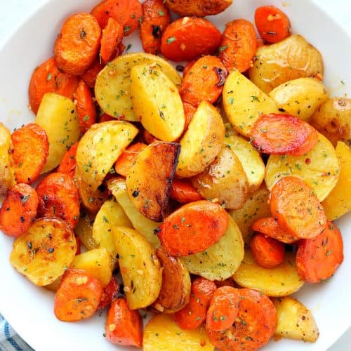 Potatoes and carrot chunks in a white bowl.