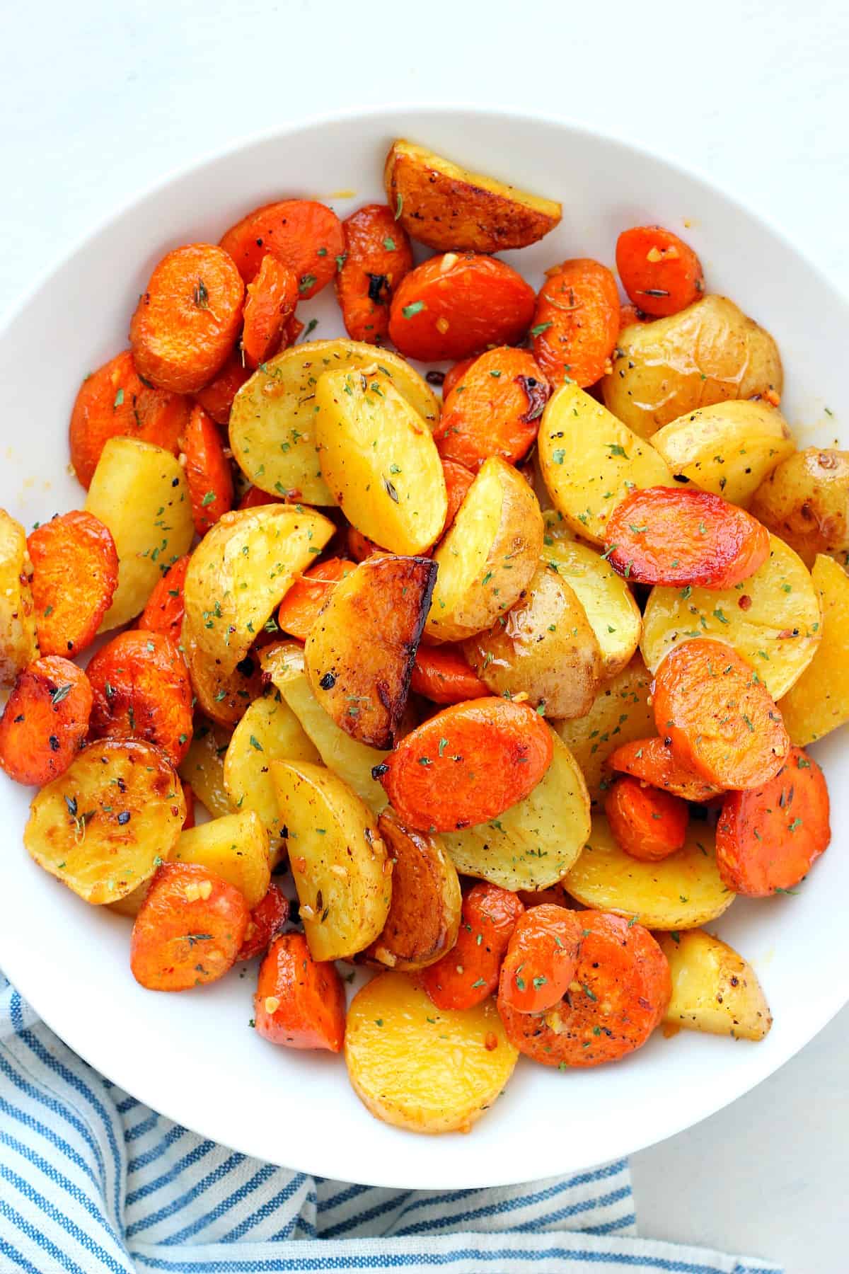 Potatoes and carrot chunks in a white bowl.