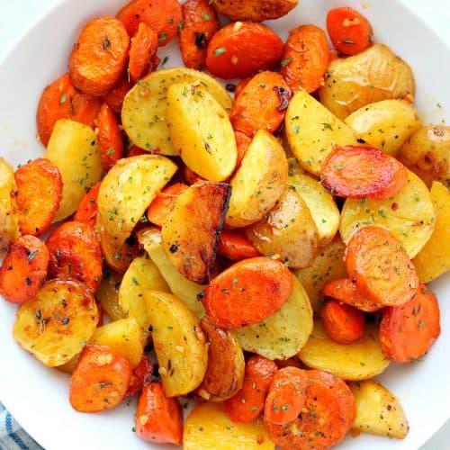 Roasted potatoes and carrots in a white bowl.