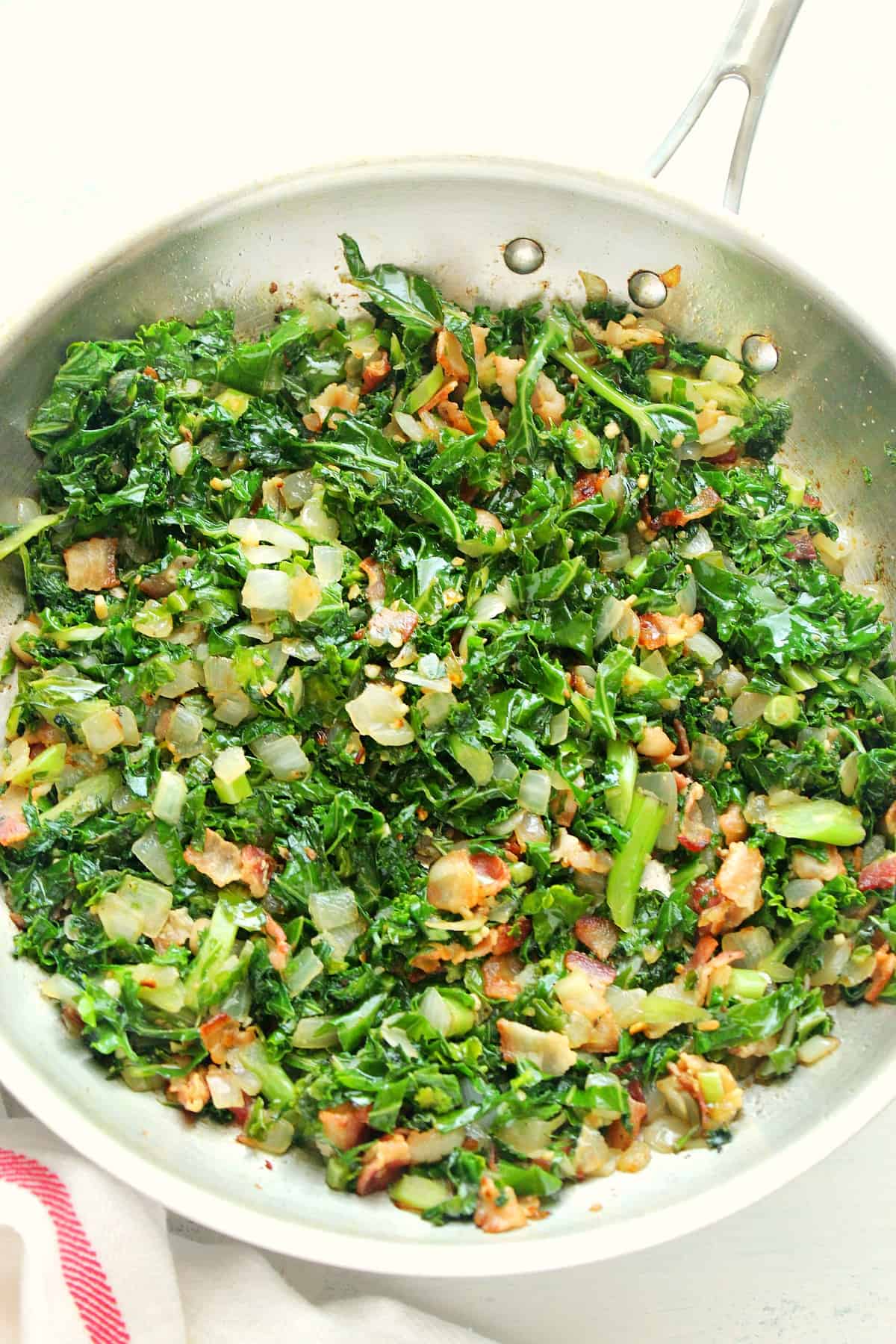 Chopped kale with bacon in a skillet.