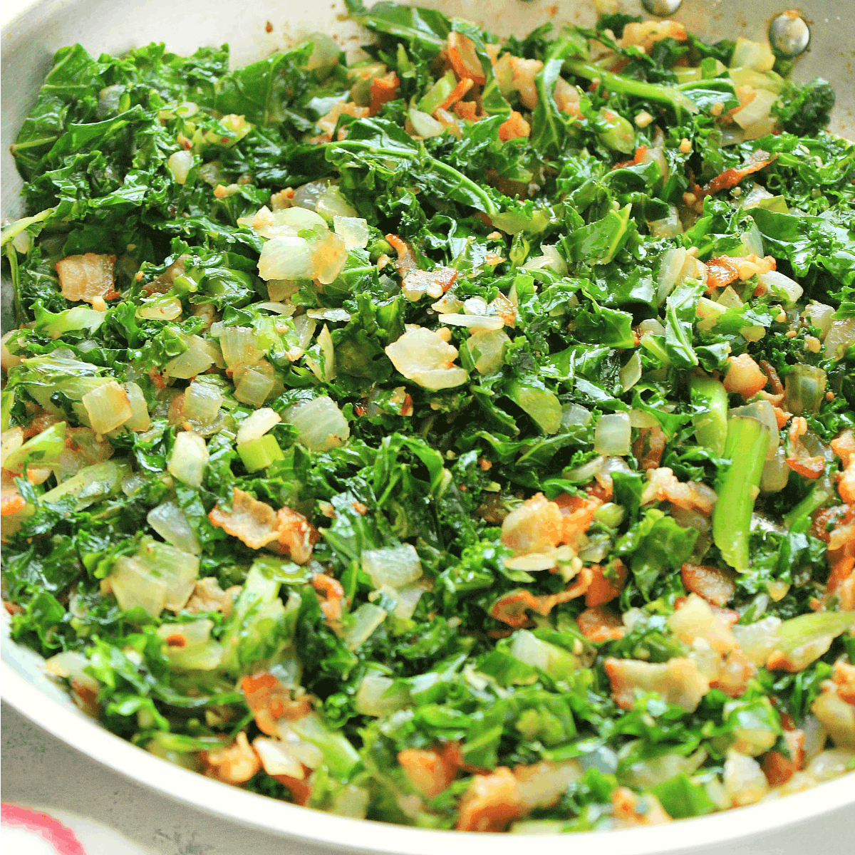 Sauteed kale with bacon in a pan.