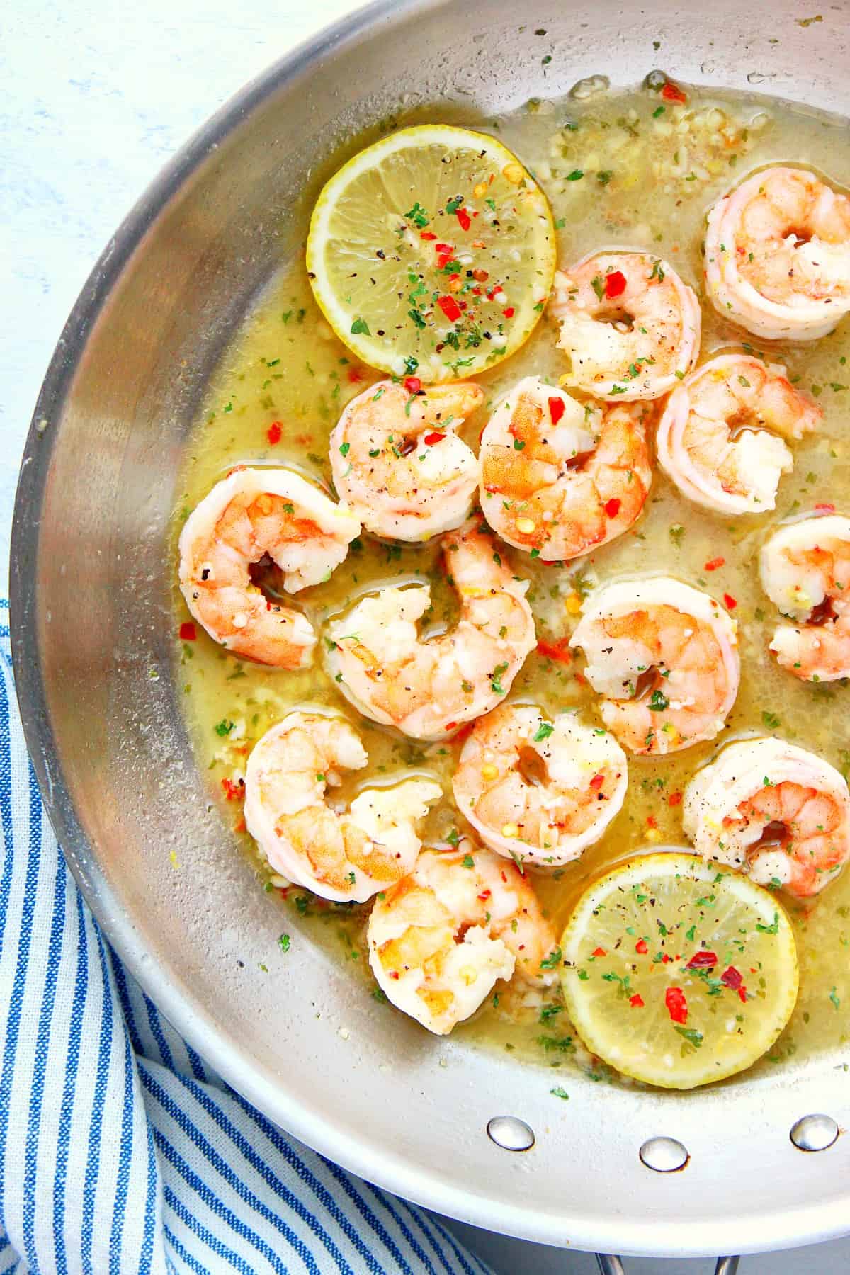 Shrimp and lemon in sauce in pan.