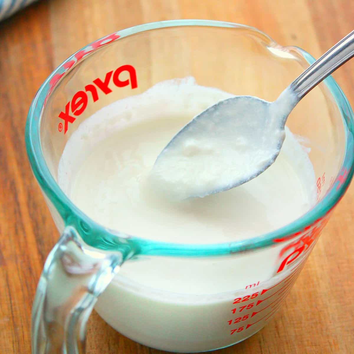 Buttermilk in glass cup with spoon.