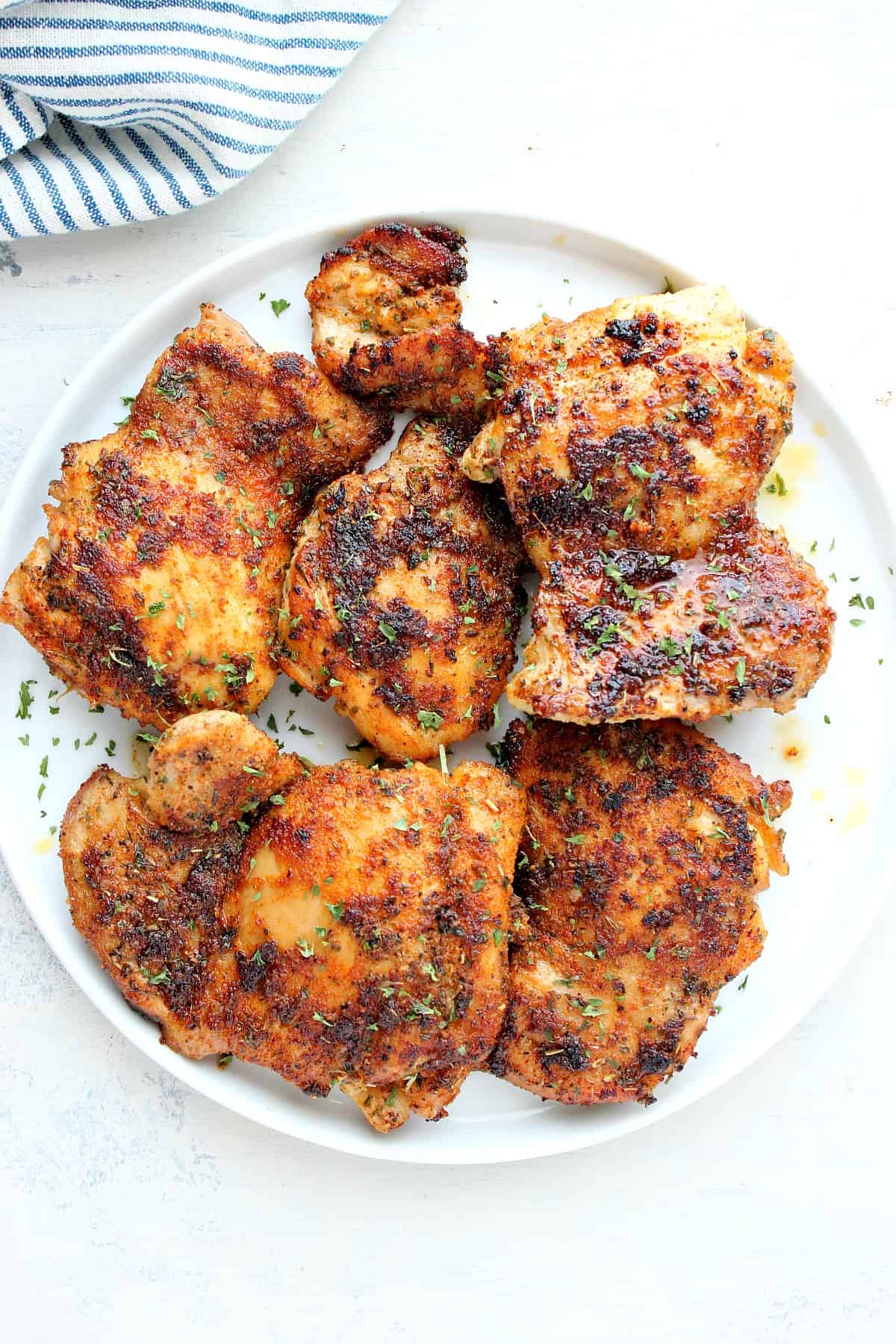 Cooked chicken thighs on a white plate.