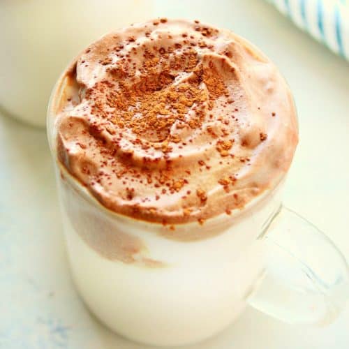 Hot chocolate with whipped topping in a glass.