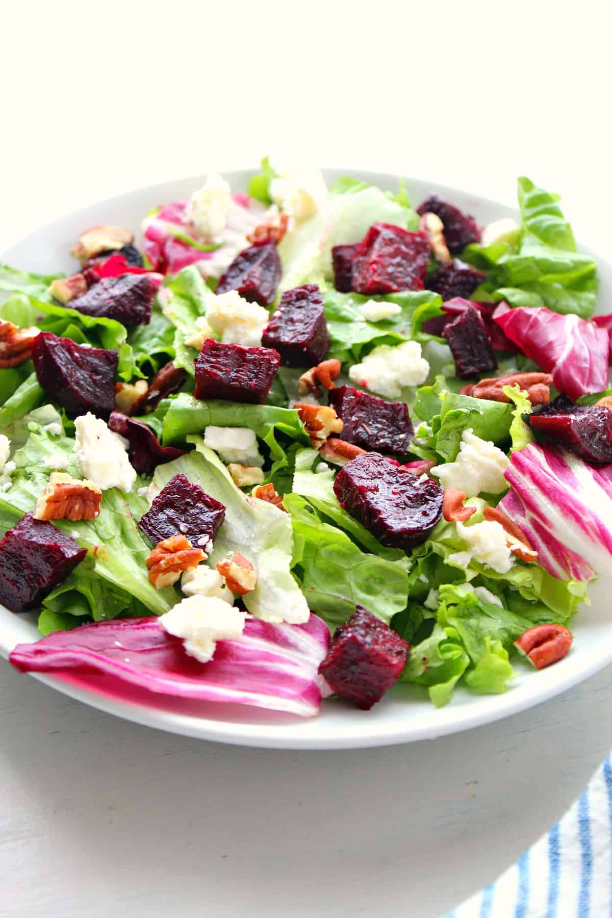 Green salad with roasted beets on a plate.