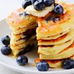 Stack of pancakes with blueberries on a plate.