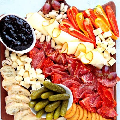 Cheeses, meats and veggies on a board.