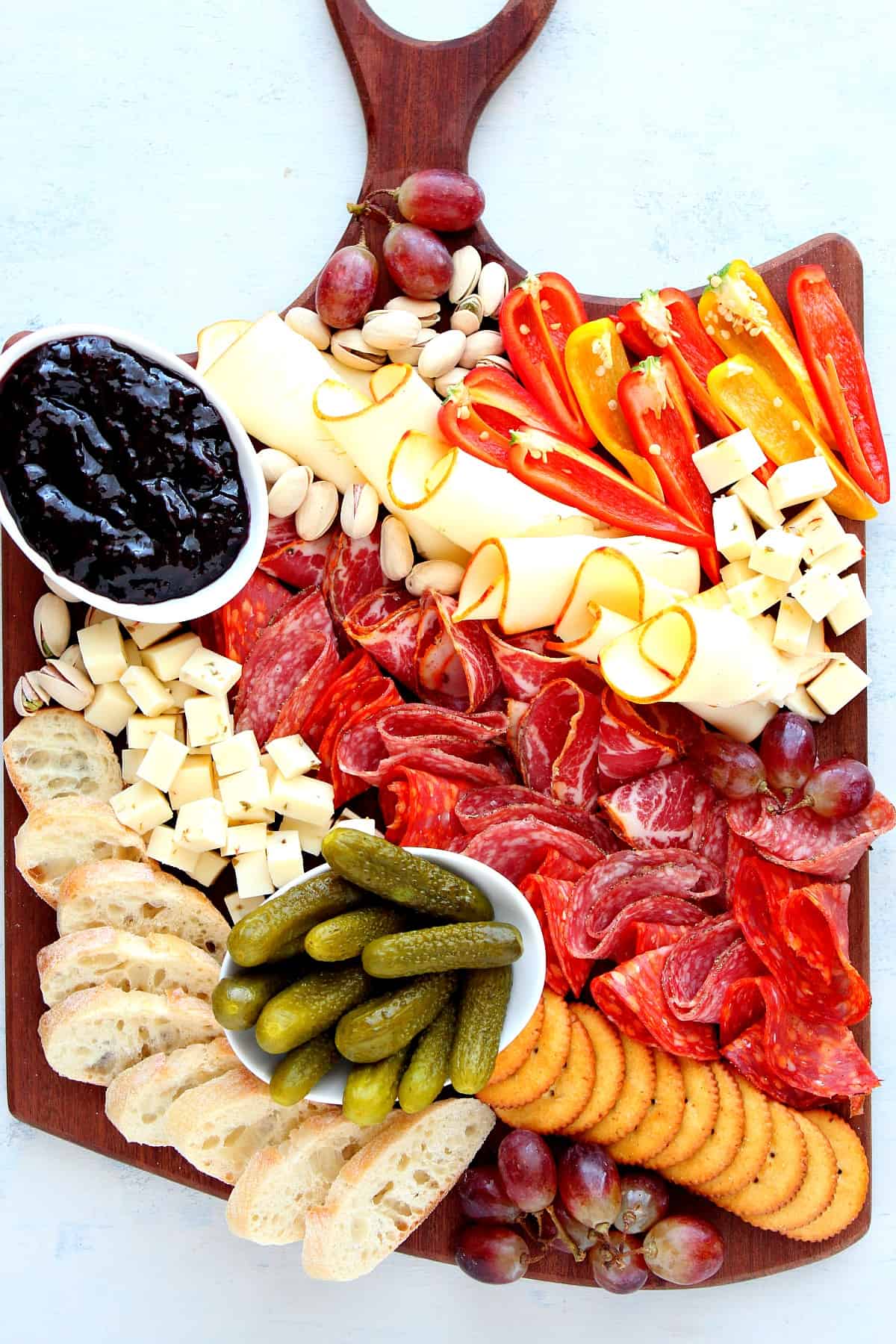 Cheeses, meats and veggies on a board.