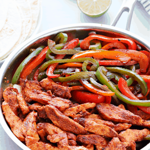 Chicken fajitas in a stainless steel skillet.