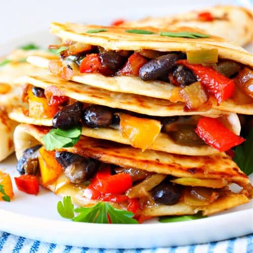 Stacked quesadillas with vegetables on a plate.