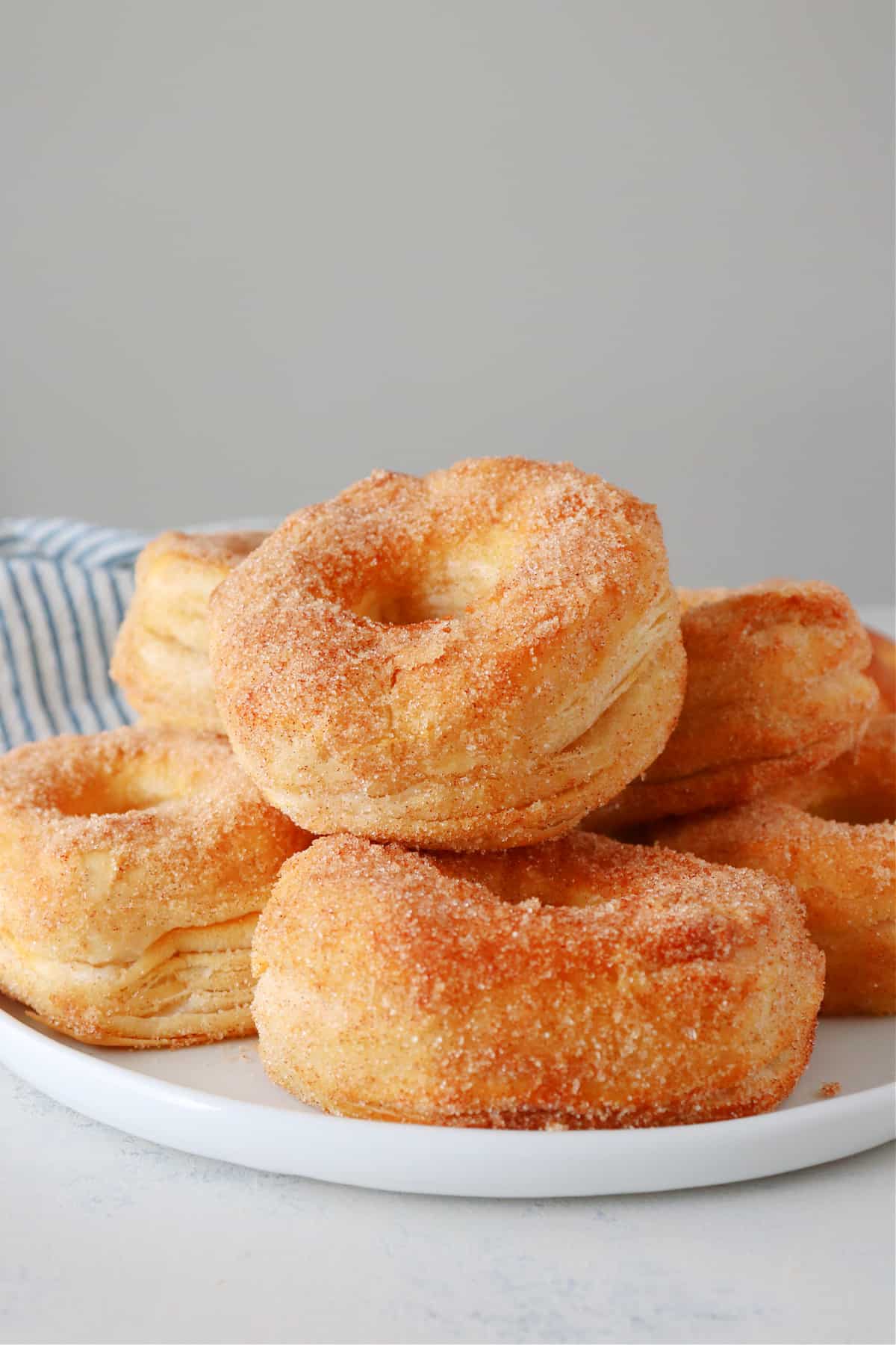 Cinnamon sugar coated donuts stacked on a plate.