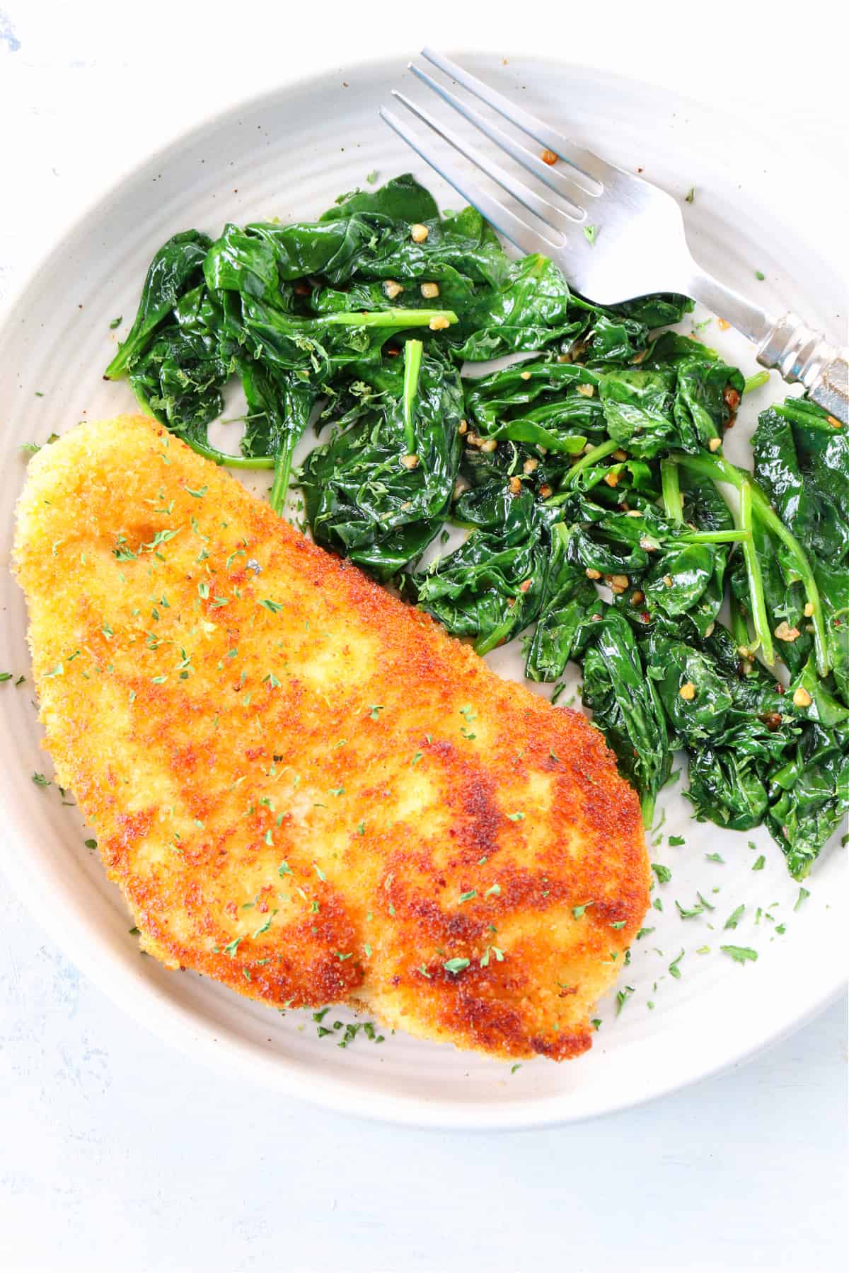 Breaded chicken and sauteed spinach on plate.