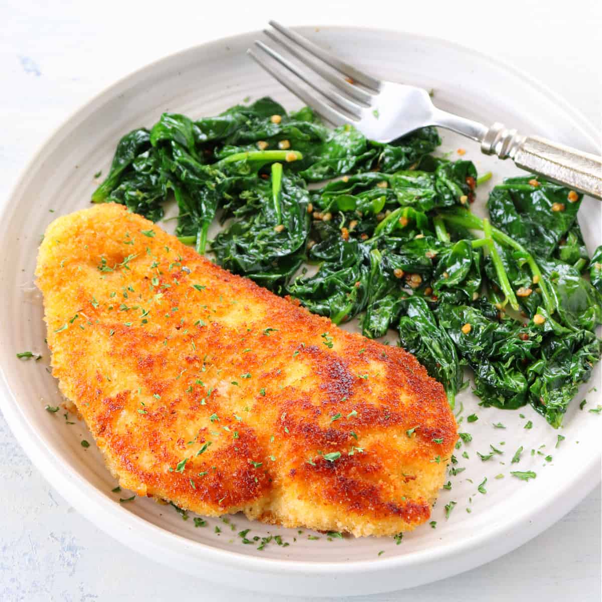 Breaded chicken on a plate with spinach.