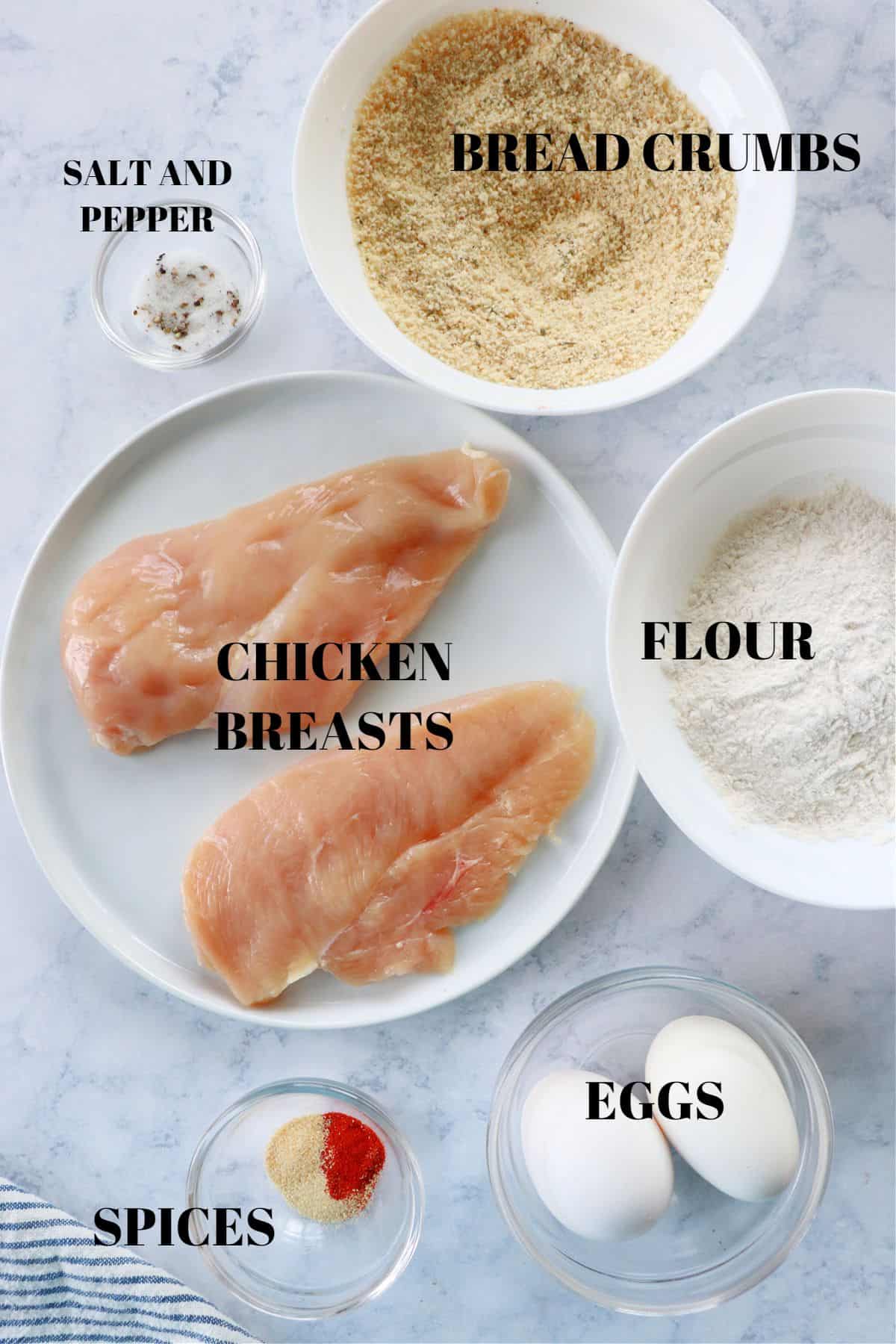 Ingredients for breaded chicken on a board.