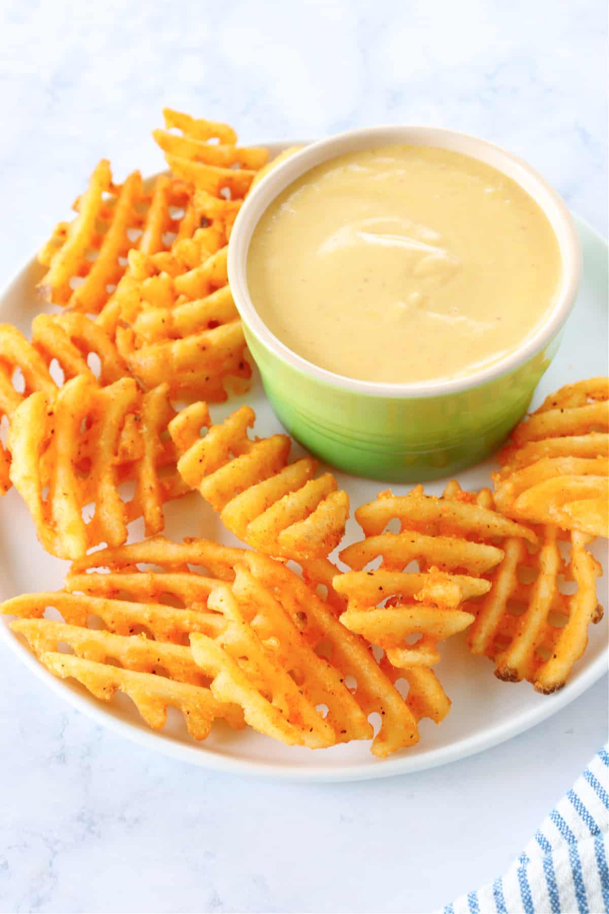 Sauce in ramekin with fries on plate.