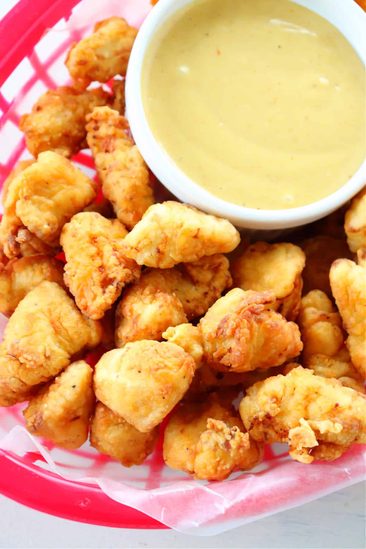 Chicken nuggets with dipping sauce in basket.