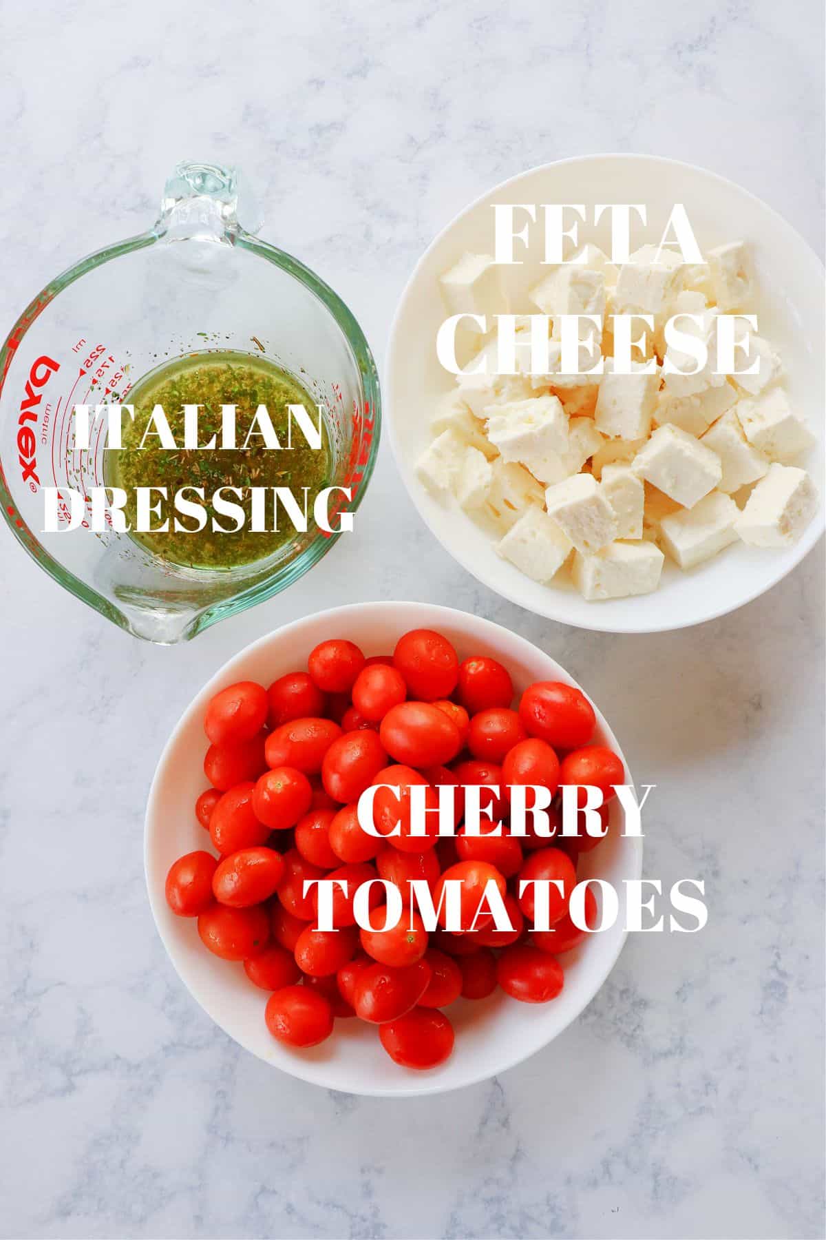 Ingredients for tomato feta salad on a marble board.