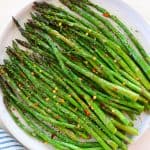 Cooked asparagus on white plate.