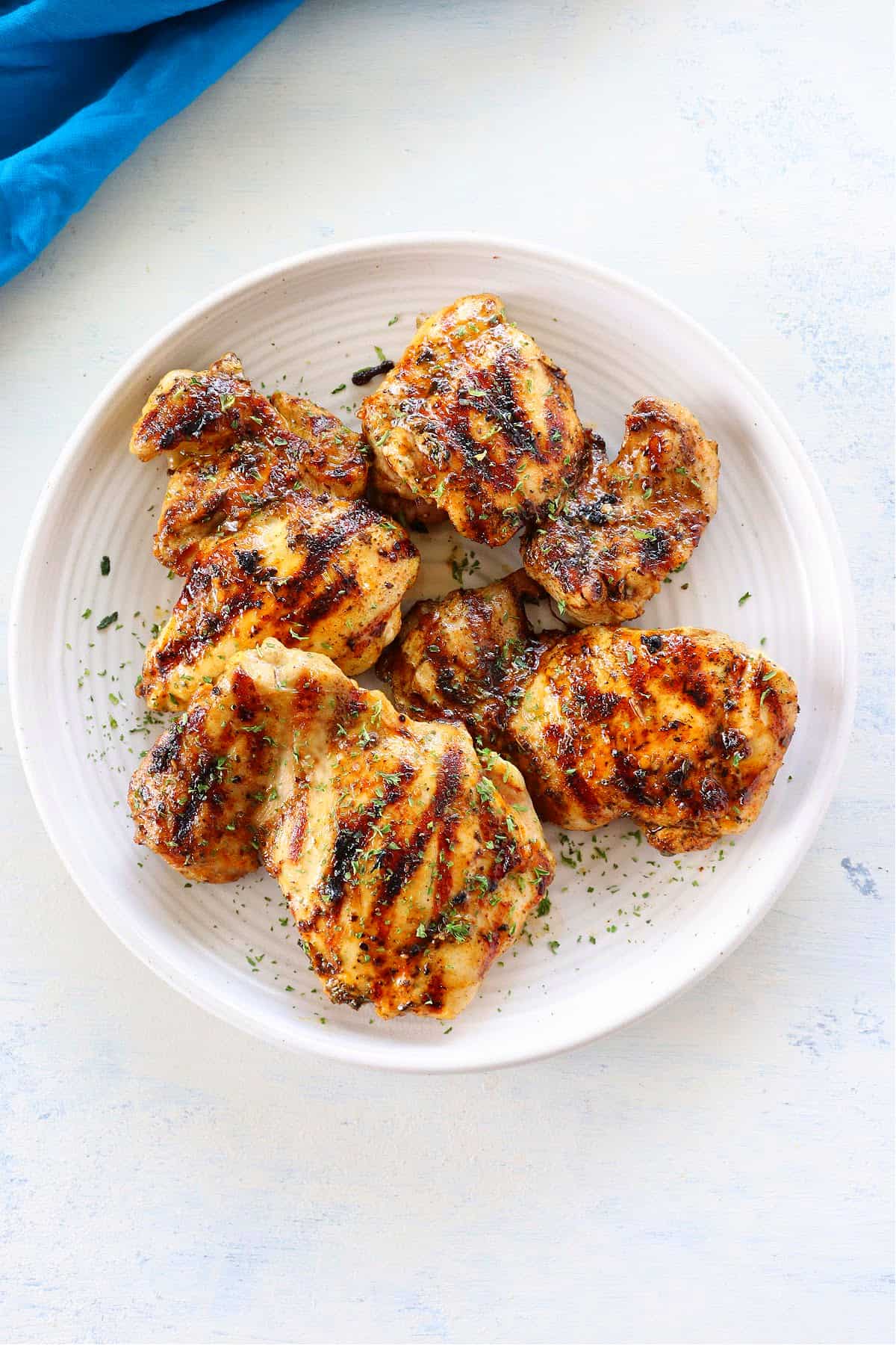 Grilled chicken thighs on white plate.