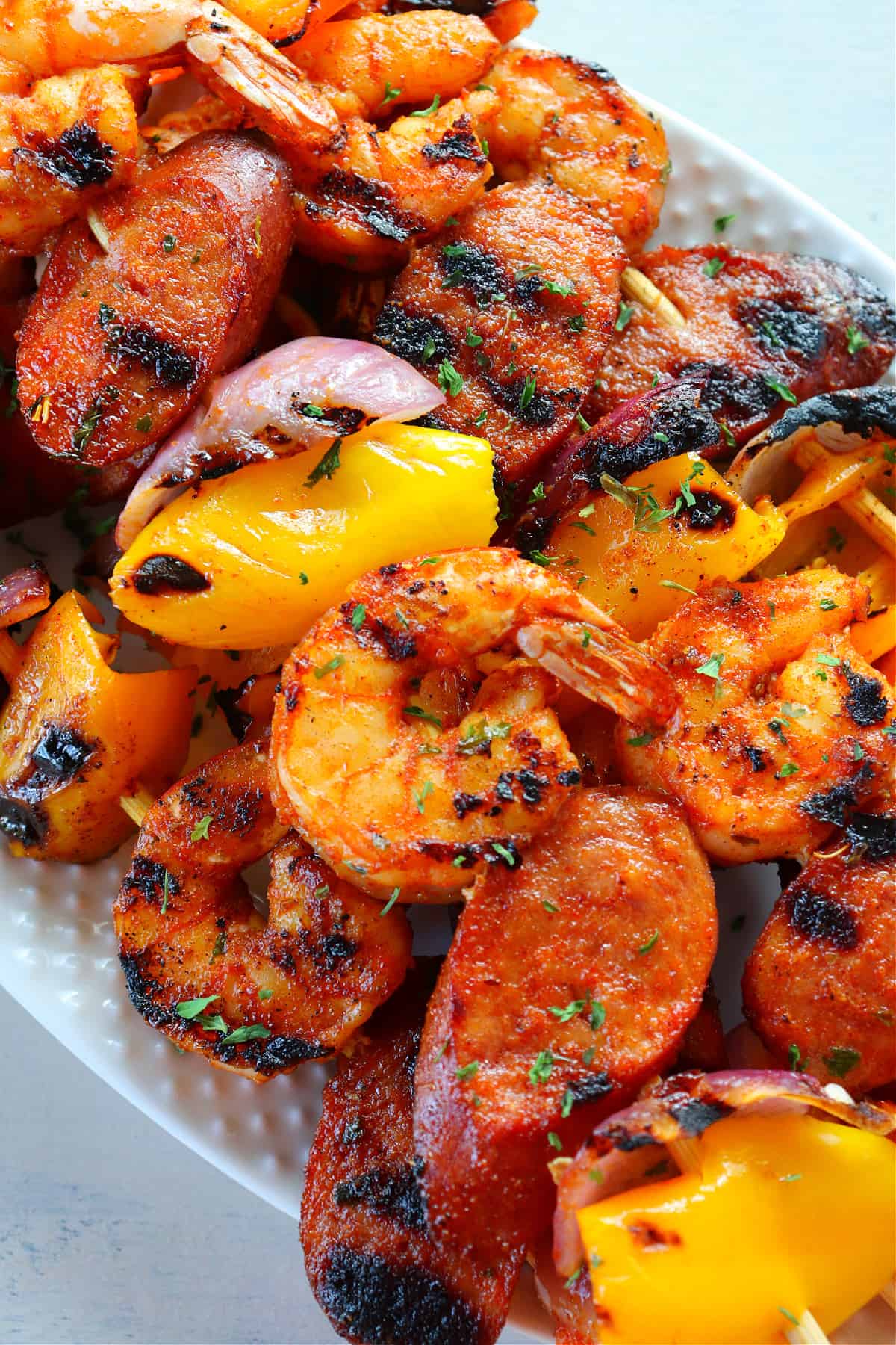 Skewers with shrimp and sausage on a plate.