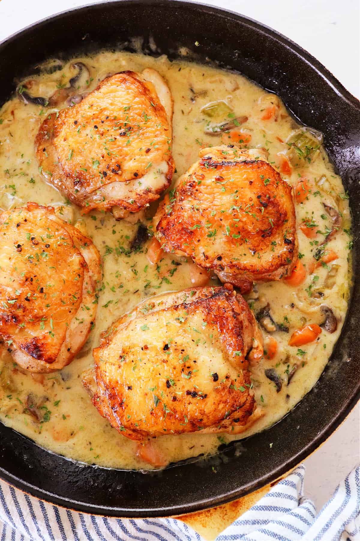 Chicken thighs in fricassee sauce in skillet.