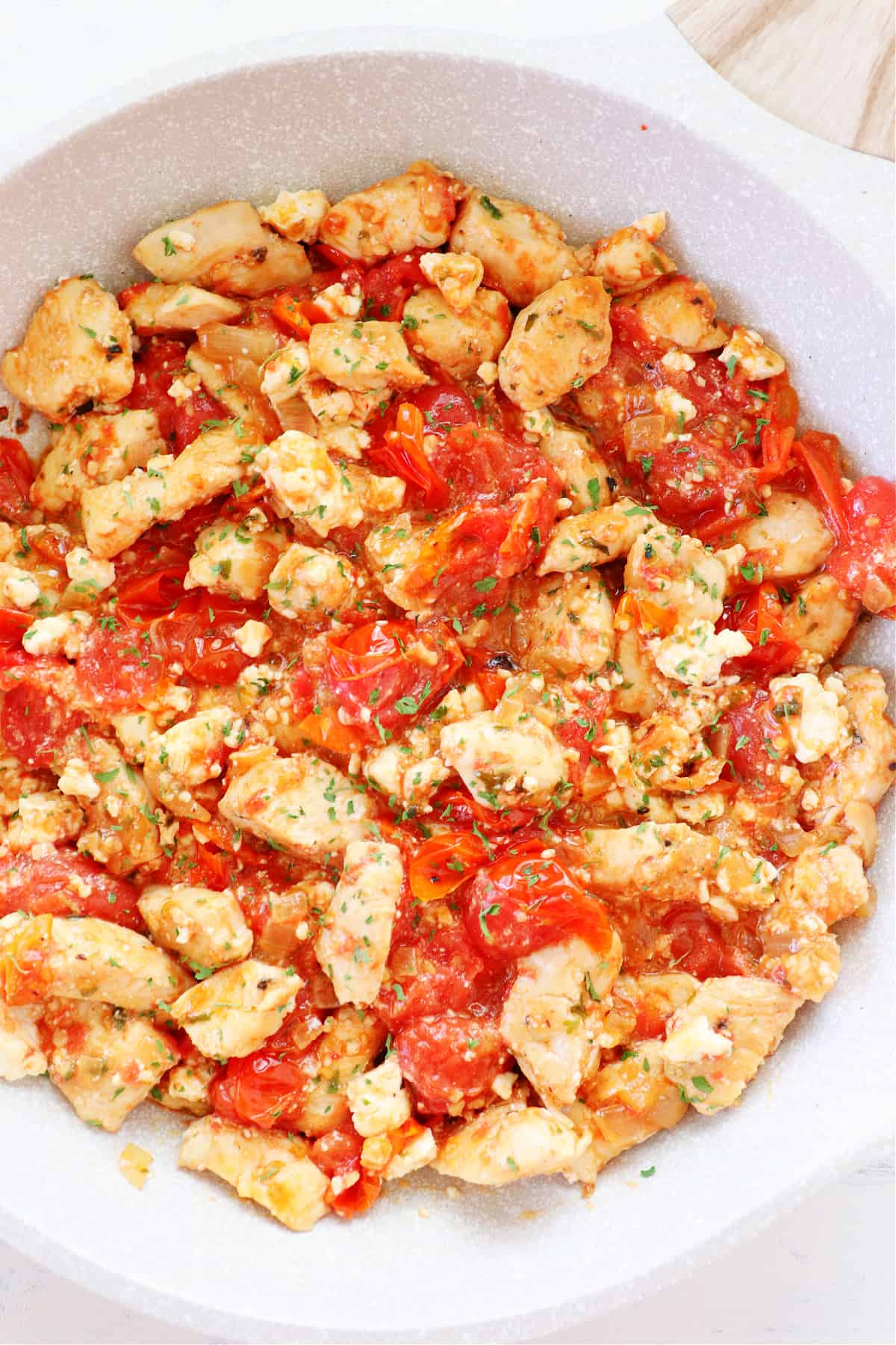 Chicken with tomatoes and feta in a pan.