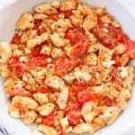 Chicken with tomatoes and feta in a skillet.