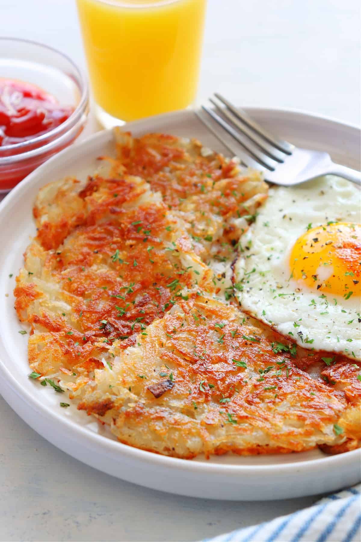 Hash browns and fried egg on a plate.