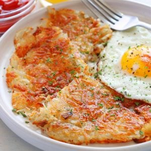 Hash browns and fried egg on a plate.