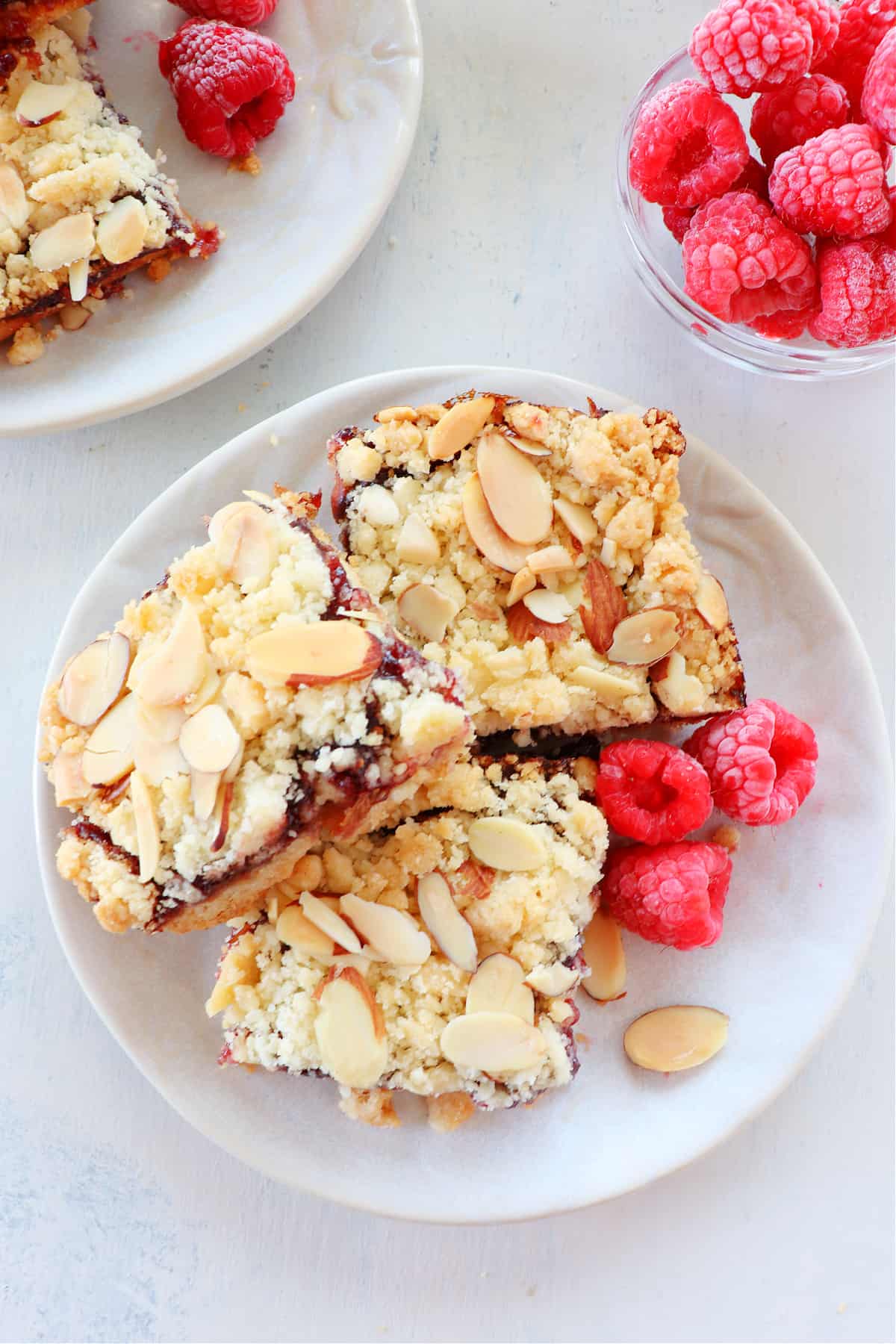 Three pieces of raspberry streusel bars on a plate.