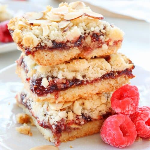 Raspberry bars stacked on a plate.