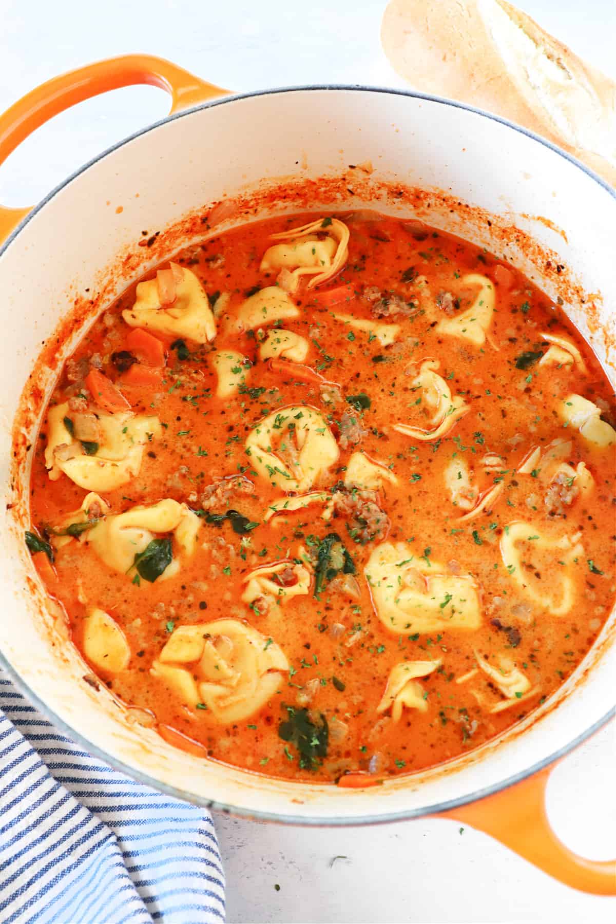 Soup with tortellini and sausage in a Dutch oven.