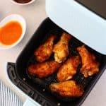 Chicken wings in the air fryer basket.