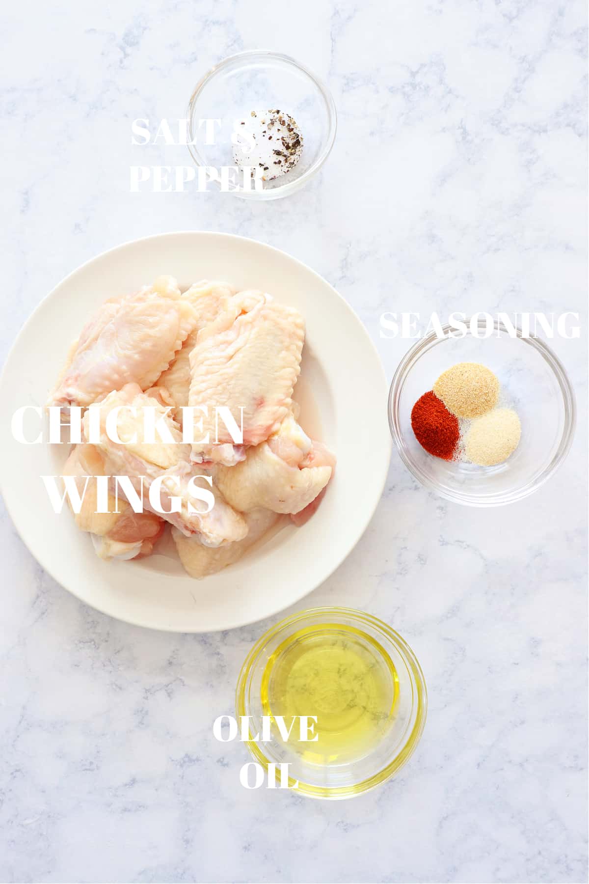 Ingredients for air fryer chicken wings on a marble board.